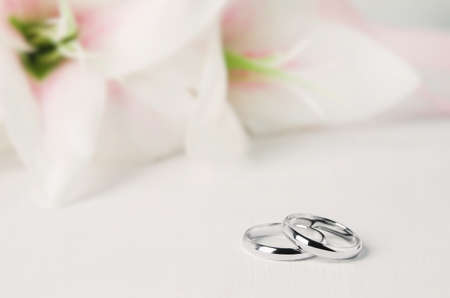 Close up of two wedding rings on white vintage wooden background with pink Lily flowerの写真素材