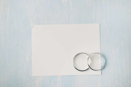 Close up of wedding rings with white card paper on blue vintage wooden table backgroundの写真素材