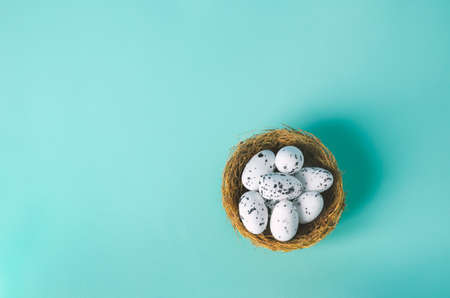 Small artificial eggs with nest on light blue background with vintage tone, Easter egg backgroundの写真素材