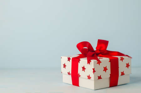 White gift box with red star pattern and red ribbon bow on blue wooden background - Christmas backgroundの写真素材