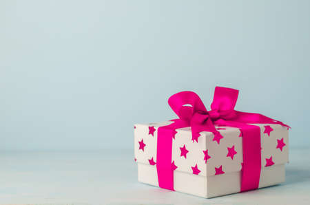 White gift box with pink star pattern and pink ribbon bow on blue wooden background - Christmas backgroundの写真素材