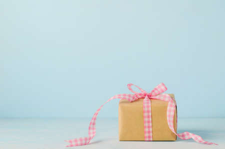 Brown gift box with pink ribbon bow on blue wooden background with soft vintage toneの写真素材