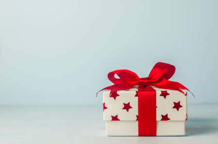 White gift box with red star pattern and red ribbon bow on blue wooden background - Christmas backgroundの写真素材
