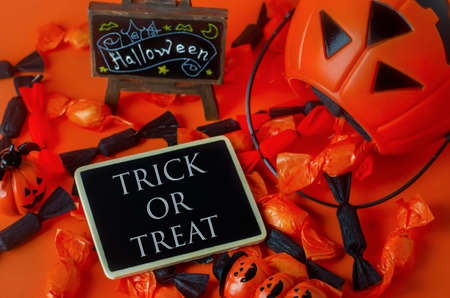 Halloween background - Trick or Treat on black wooden tag with pumpkin bag and black and orange...
