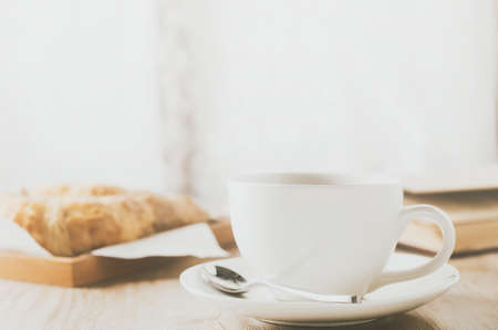 Close up of white coffee cup with croissant on wooden table with vintage and vignette toneの写真素材
