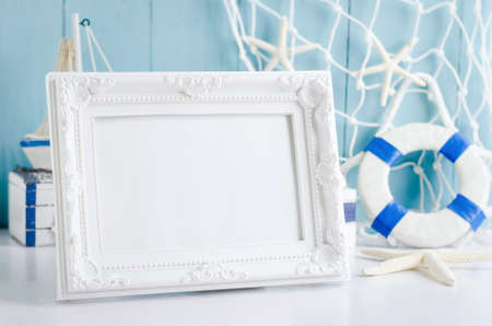 Close up of vintage picture frame with sail boat Toy model, rope and seashell on white and blue wooden background - Nautical backgroundの写真素材