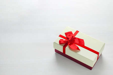 Close up of two tone gift box with red ribbon bow on white wooden backgroundの写真素材