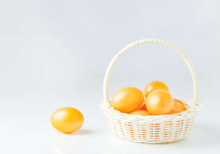 Close up of golden easter eggs at white basket on whiteの写真素材
