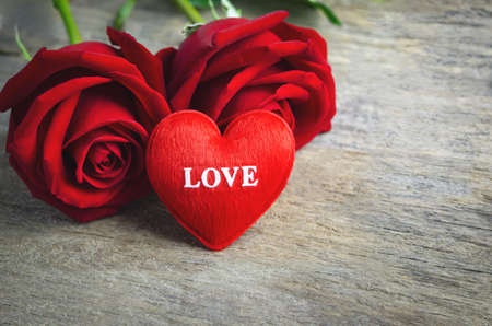 Red heart with love text and red rose flowers on wooden background, Valentine's rosesの写真素材