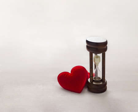 Antique wooden hourglass with red hearts on white wooden table, Time conceptの写真素材