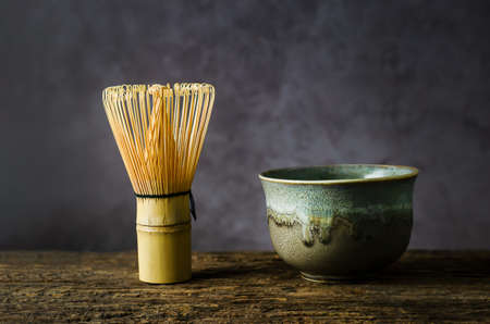 Japanese matcha green tea at homemade clay bowl with bamboo whisk on wooden table with vignette toneの写真素材