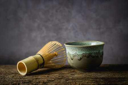 Japanese matcha green tea at homemade clay bowl with bamboo whisk on wooden table with vignette toneの写真素材