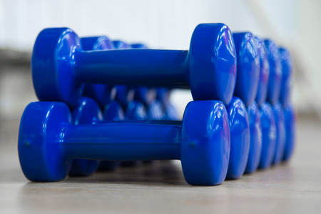 Stack of blue dumbbells on the floor in sports hallの写真素材