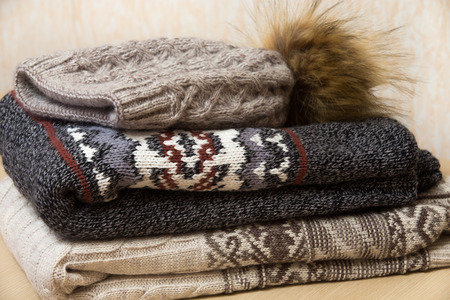 Two folded winter sweaters and woolen hat with bubo neatly arranged on each other