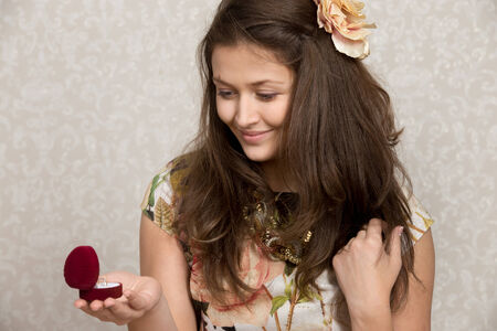 Smiling girl looks at the ring in heart shaped box