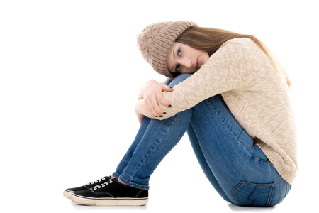 Sad teenage girl with problems sitting with her head on her knees, copy spaceの写真素材