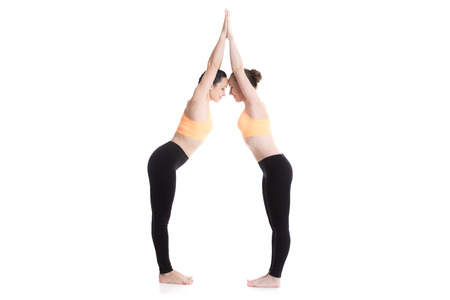 Two beautiful sporty girls together in orange bright sportswear happy smiling, joining hands,...