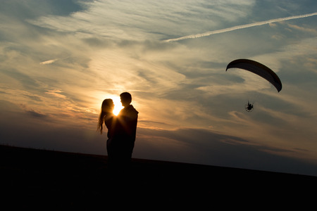 Couple of lovers against vast skyline on the sunset or sunrise, hugging each other, standing on the...