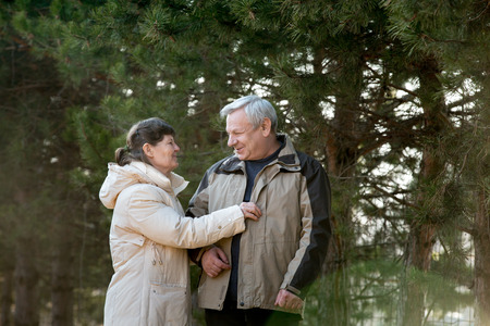 Senior couple enjoying a walk in park, laughing, joking, looking at each other with love, elder lady...