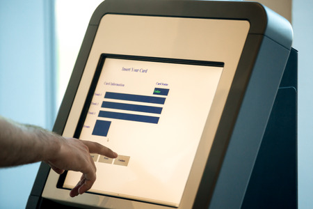 Close up of male hands touching interactive display at self-service transfer machine, doing...