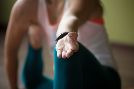 Sporty beautiful young woman in sportswear working out indoors, doing variation of Yoga Dandasana Posture, close-up, focus on fingers in Jnana mudra, horizontal imageの写真素材