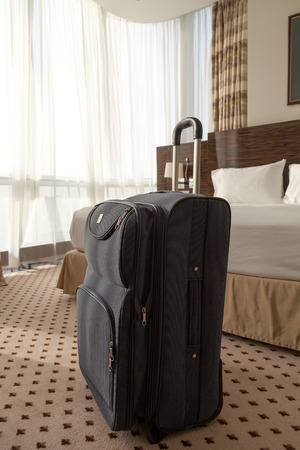 Large blue wheeled suitcase standing on the floor in the hotel room. Vertical imageの写真素材