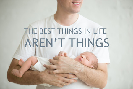 Close-up portrait of new born baby sleeping in male arms. Young happy father holding baby smiling....