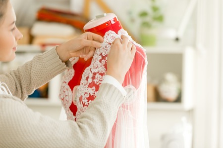 Woman dressing a tailor dummy mannequin in a lace cloth. Concept photo, over a shoulderの写真素材