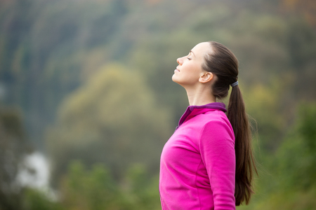 Portrait of a young woman outdoors in a sportswear, head up, her eyes closed. Concept photo, copy spaceの写真素材