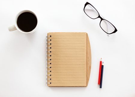 White office desk with a notebook and pencils, glasses on it. Top view with copy spaceの写真素材