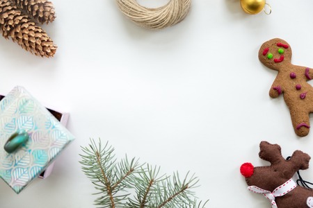 Flat view of Christmas decoration, cones, fir tree branch, gift box, twine, glass ball, ginger man, Rudolph the Red Nosed Reindeer toy. Space for a text or design in the middle. Christmas concept, copy spaceの写真素材