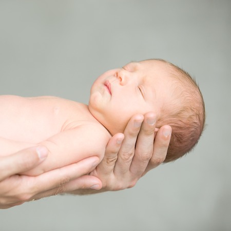 Portrait of a sleeping newborn hold at hands. Family, healthy birth conceptの写真素材
