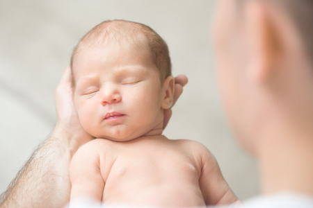Portrait of a newborn hold in father palms, eyes closed. Family, healthy birth concept photo. View over the shoulderの写真素材