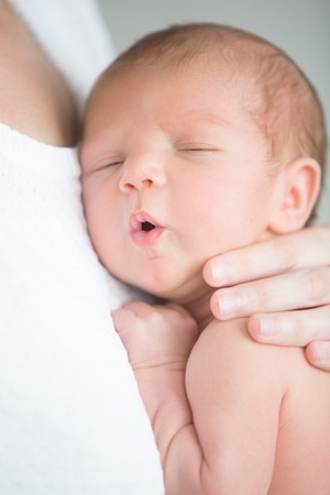 Portrait of a cute newborn hold at mother s breast, his mouth open. Family, healthy birth concept...
