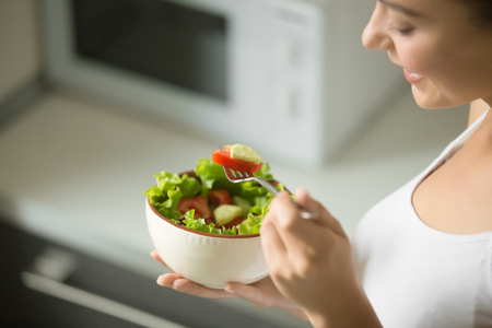 Bowl of fresh green salad hold in female hands, close up. Weight loss conceptの写真素材