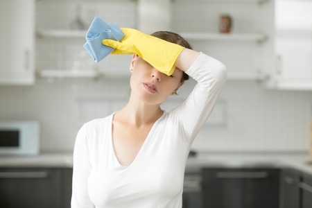 Tired and exhausted woman, frustrated with doing much work about the house resting for a minute or wiping her forehead after finishing work. Home, housekeeping conceptの写真素材