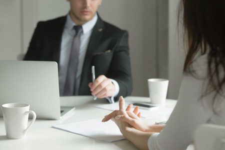 Close up of business people hands hold at an office desk, young man and woman are having a business talk. The woman feels stressed. Business concept photoの写真素材