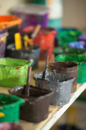Close-up of silk screen printing ink collection on the shelf hold in plastic containers. Open cans with colorful paints in silkprinting professional workshop print house. Vertical imageの写真素材