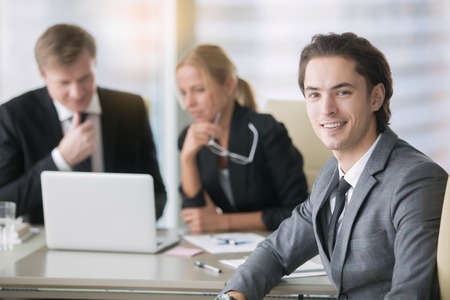 Portrait of businessman with group of subordinates at the background. Teamwork, conflict solution...