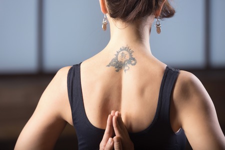 Young attractive woman practicing yoga, making namaste behind the back, working out, wearing...