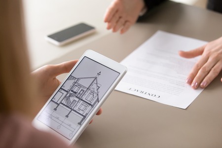 Real estate agency clients holding tablet, looking at architectural plan of dream house, considering...