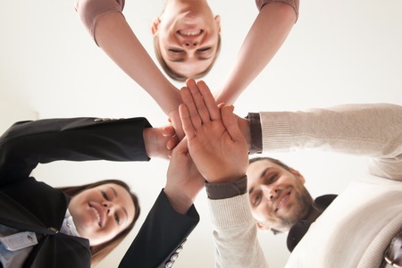 Bottom view of hands put together, looking down at camera, team of happy smiling entrepreneurs united by common project, team building activity, achieve success together, successful business planの写真素材