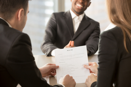 Employers or recruiters review cv of black confident job applicant smiling at background during employment interview, good resume template writing tips, hire me, starting building career, close upの写真素材