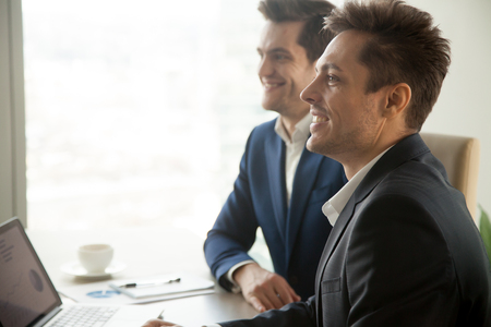 Smiling attentive businessmen attending conference meeting, listening to speaker at presentation, audience of financial training or business seminar, accounting courses, side view, copy spaceの写真素材