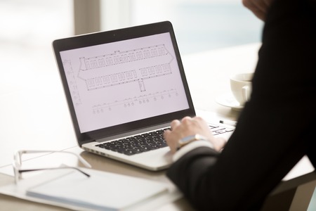 Close up view of businessman working with architectural building plan, considering car parking area investment, focus on laptop screen, indoor park space digital blueprint with lot of parked autosの写真素材