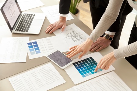 Close up view of Interior designers teamwork with pantone swatch and house building plans on office desk, architects working with blue color palette to choose best paint for home refurbishmentの写真素材