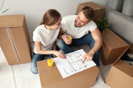 Happy couple discussing house plan looking at blueprint planning new home interior design, happy...