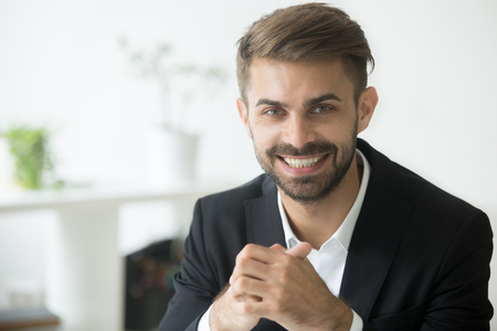 Smiling attractive young millennial businessman wearing suit looking at camera, optimistic cheerful coach, happy ambitious professional manager, sales person or business expert head shot portraitの写真素材