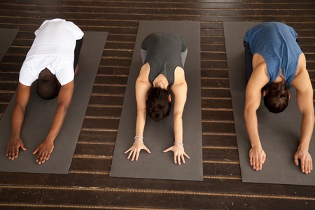 Group of three young sporty afro american and caucasian people practicing yoga lesson stretching in Child exercise, Balasana pose, working out, indoor, studio top view. Healthy lifestyle conceptの写真素材
