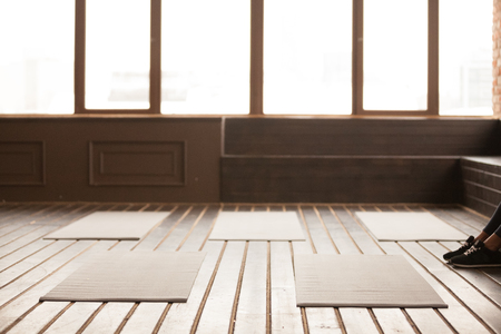 Studio with yoga mats on wooden floor, modern gym space room for stretching pilates sport workout exercises indoors or meditation practices with trainer coach waiting for group fitness training classの写真素材